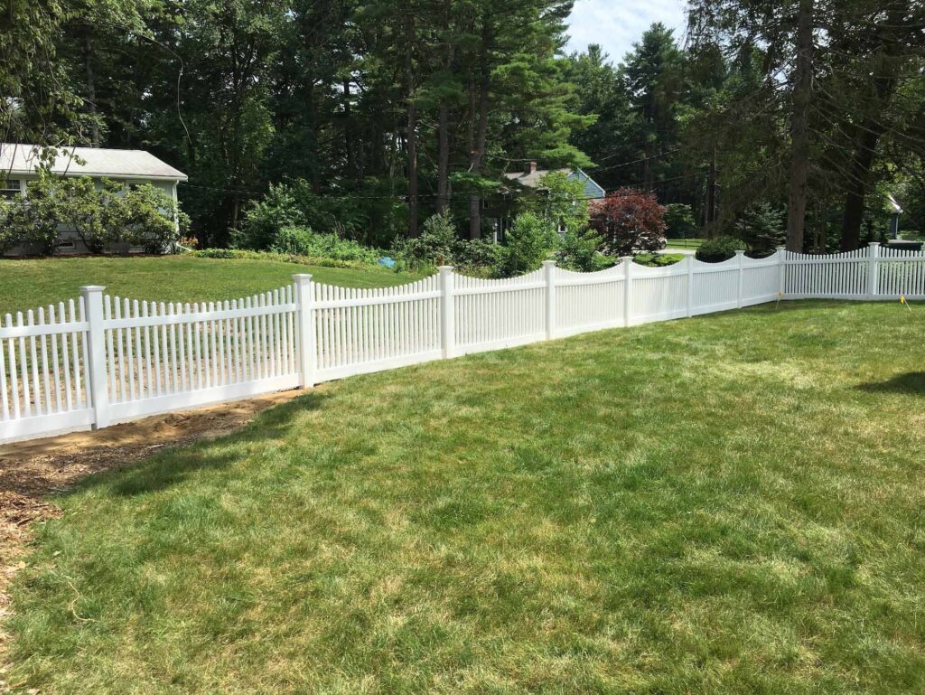 Chestnut scallop white picket fence in a large yard
